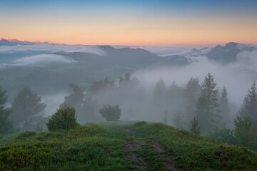 Mountain landscape with fog after rain, peaks in the fog. Beautiful, colorful spring panorama of Pieniny Mountains and Tatra Mountains in the fog and morning light, Poland, Slovakia