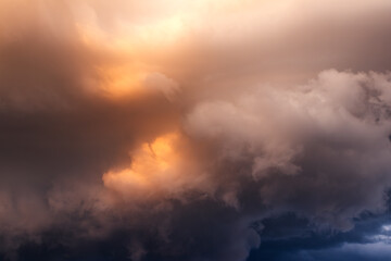 Obraz premium Stormy clouds illuminated by sunset golden light. Cloudscape thunderstorm background. Dramatic sky in extreme weather