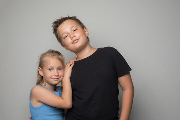 Smiling siblings, brother and sister hugging and posing over white background