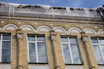 Long icy icicles hanging from the edge of a roof, catching the cold winter light.
