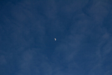 A small glowing moon floats in the center of a deep blue twilight sky, minimal and serene.