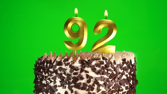 Burning candles number 92 on birthday cake against chroma key background. Ninety-second birthday. Birthday and anniversary celebration