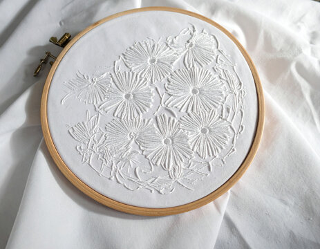 The delicate Chikankari embroidery from Lucknow, with its intricate white-on-white patterns, is showcased on a fine fabric, highlighting the region's refined textile tradition.