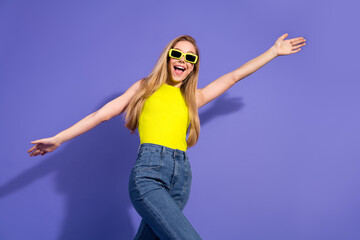 Joyful young woman wearing vibrant yellow top on a colorful background celebrating in relaxed style...
