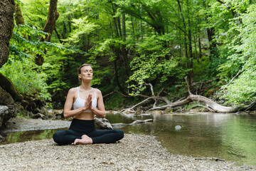 Young woman meditating and practicing yoga on nature. Holistic Health and Mental Well-Being.