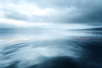 A calm river reflecting an overcast sky, with soft ripples breaking the symmetry of the reflection.