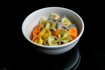 colorful farfalle pasta in a bowl on white marble background