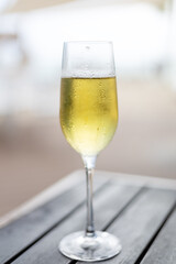 Enjoying sparkling drink in a chilled glass on a wooden table during a sunny afternoon by the beach