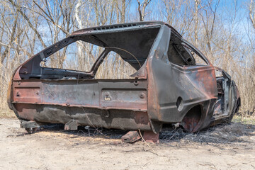 Burnt and rusty charred car close-up. Damaged automobile in consequence of accident and disaster....