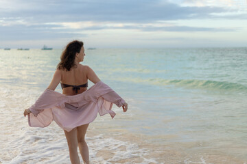 Woman enjoying a peaceful moment by the beach during sunset with gentle waves lapping at her feet