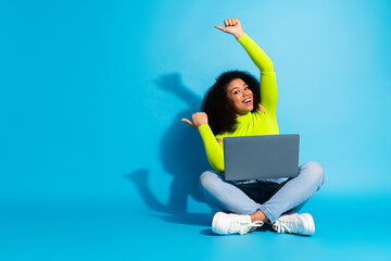 Cheerful young woman with laptop enjoying leisure on a blue background in casual style