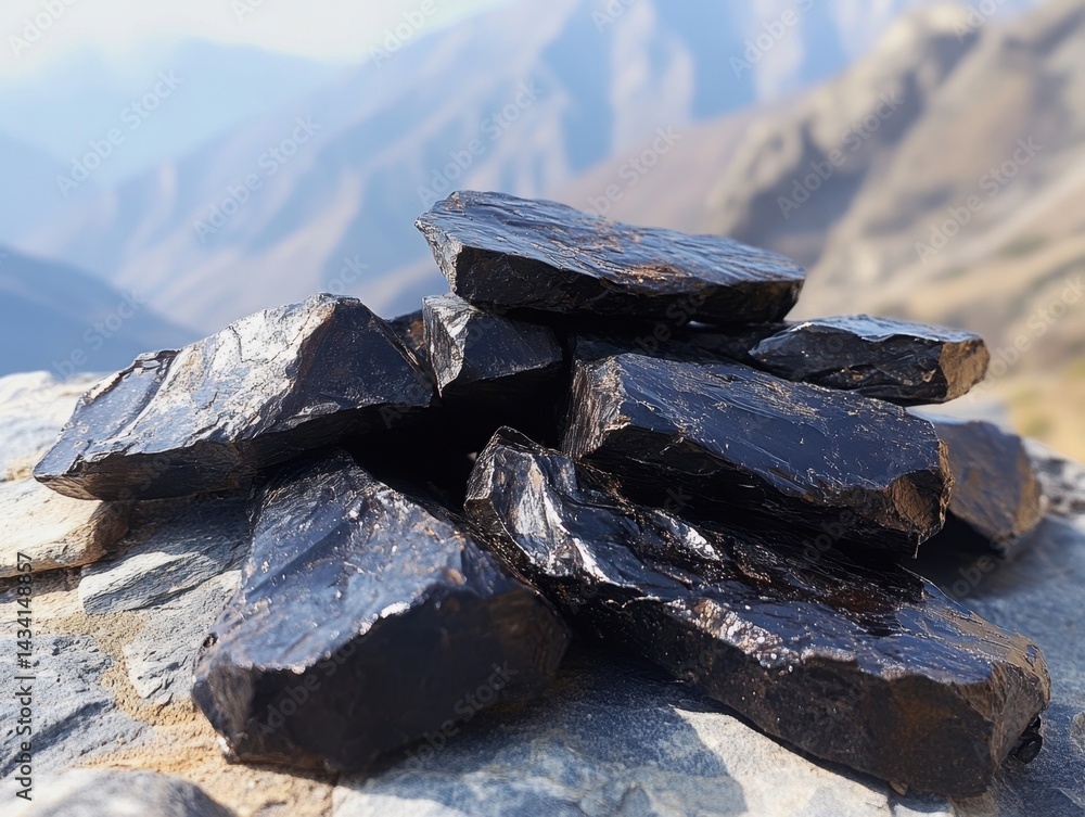 Poster stack of obsidian rocks on a mountain peak with a blurred mountain range background in natural light