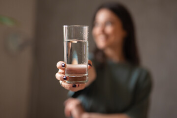  Woman holding a glass of water towards camera