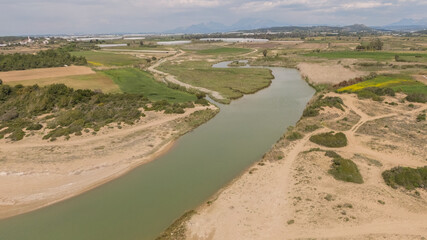 A river with dunes and bushes around it, cloudy sky in Antalya, Turkey.