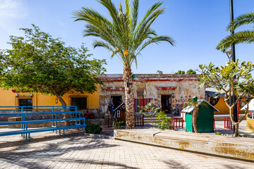 Village square with old houses or buildings in background, one with yellow wall in good condition and other with walls damaged by passage of time, sunny day in Loreto, Baja California Sur, Mexico