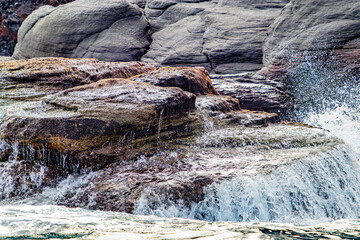 Foamy seawater lapping over huge boulders on Mexican coast of Coronado Island, waves breaking over...