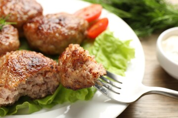 Eating delicious patty at wooden table, closeup