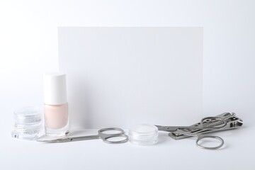 Set of different manicure tools and blank card on white background, closeup