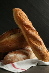 Different types of fresh bread on dark textured table, closeup