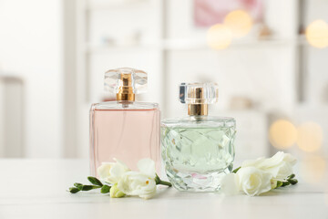 Bottles of perfume and beautiful flowers on white table