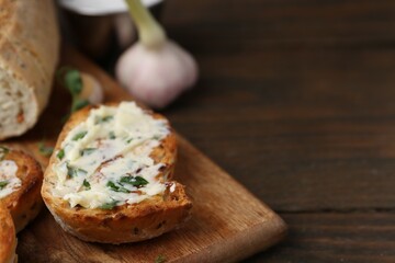 Tasty bread with garlic, herbs and oil on wooden table, closeup. Space for text