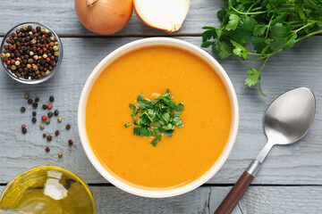 Delicious lentil cream soup with parsley served on grey wooden table, flat lay