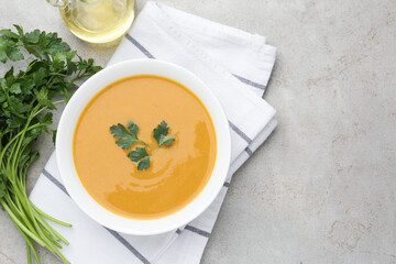 Delicious lentil cream soup with parsley and oil on light grey table, flat lay. Space for text