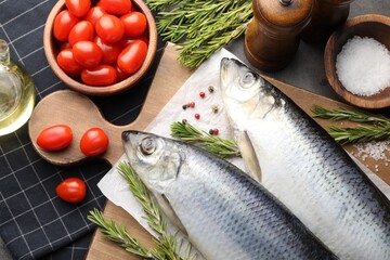Salted herrings, spices and tomatoes on grey table, flat lay