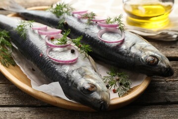 Tasty herrings with spices on wooden table, closeup