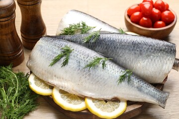 Tasty herring fillets with dill and lemon slices on wooden table, closeup