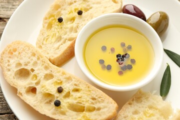 Slices of bread with oil, spices and olives on wooden table, closeup