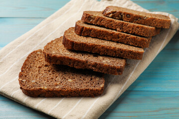 Pieces of fresh bread on light blue wooden table, closeup