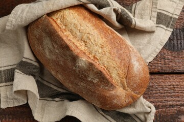 Fresh loaf of bread on wooden table, top view
