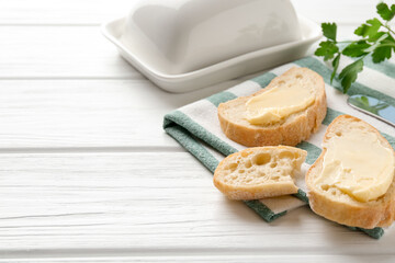 Slices of bread with butter on white wooden table. Space for text