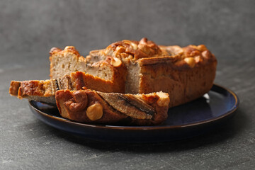 Cut banana bread with nuts on black table, closeup