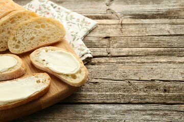 Pieces of bread with butter on wooden table. Space for text
