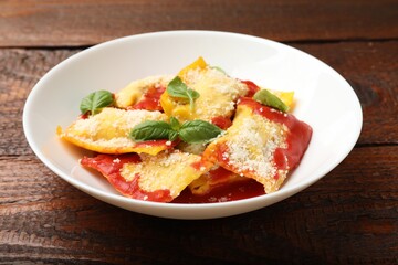 Delicious ravioli with tomato sauce, parmesan cheese and basil on wooden table, closeup