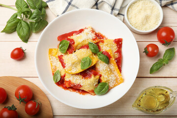 Delicious ravioli with tomato sauce, parmesan cheese and basil on white wooden table, flat lay
