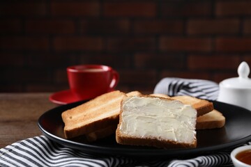 Slices of tasty toasted bread with butter on wooden table against dark background, closeup