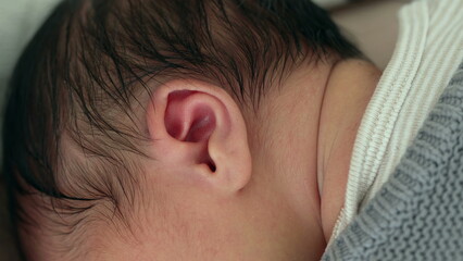 Close-up of a newborn baby's ear nestled against a blanket, showcasing the delicate features and soft skin of early infancy in a cozy, nurturing environment