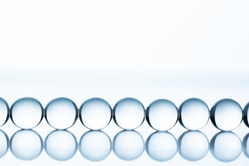 Blue collagen molecules in a raw on white background with copy space. Hyaluronic acid skin care, collagen serum drop.