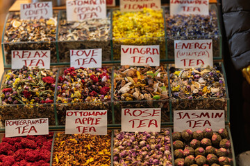 Variety of loose herbal teas with handwritten signs on a spice market stand. Natural dried flowers...