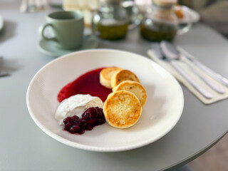 Traditional syrniki served with cherry sauce and sour cream. Homemade comfort, breakfast and cozy morning rituals