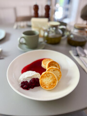 Traditional syrniki served with cherry sauce and sour cream. Homemade comfort, breakfast and cozy morning rituals