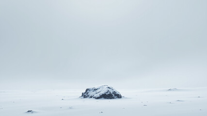 The image shows a large rock in the middle of a snow covered field