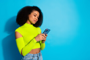 Fototapeta na wymiar Young woman in neon top using smartphone against a blue background, embodying modern style, fashion, and vibrant youthfulness.