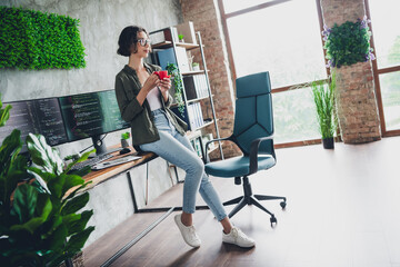 Young Professional Woman Drinking Coffee in a Cozy Workspace with Modern Computer Setup and Stylish...