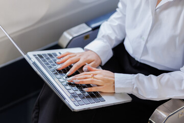A determined businesswoman sits on a flight, visibly stressed as she rushes to polish her report...