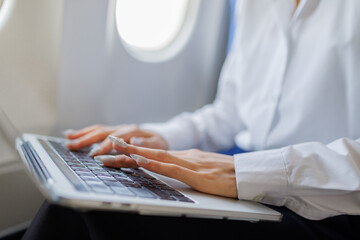 A determined businesswoman sits on a flight, visibly stressed as she rushes to polish her report...