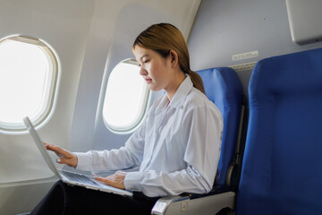 A determined businesswoman sits on a flight, visibly stressed as she rushes to polish her report...